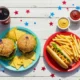 Jedzenie amerykańskie na stole: burgery, frytki, hot dogi i cola, a także amerykańskie flagi